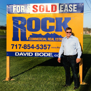 AquaPhoenix employee in front of sold sign for new location